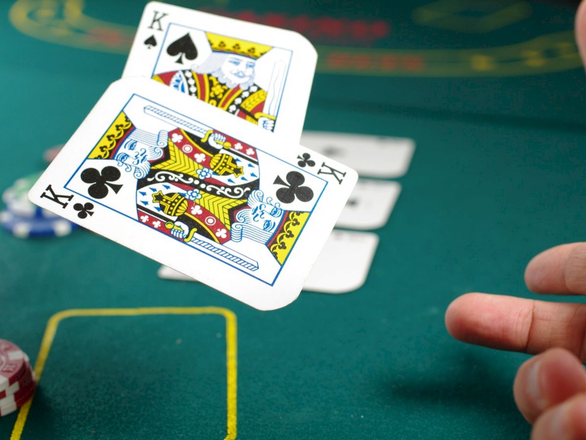 A hand of poker with two Kings (King of spades, King of clubs) being played, while poker chips are visible on the table in the background.