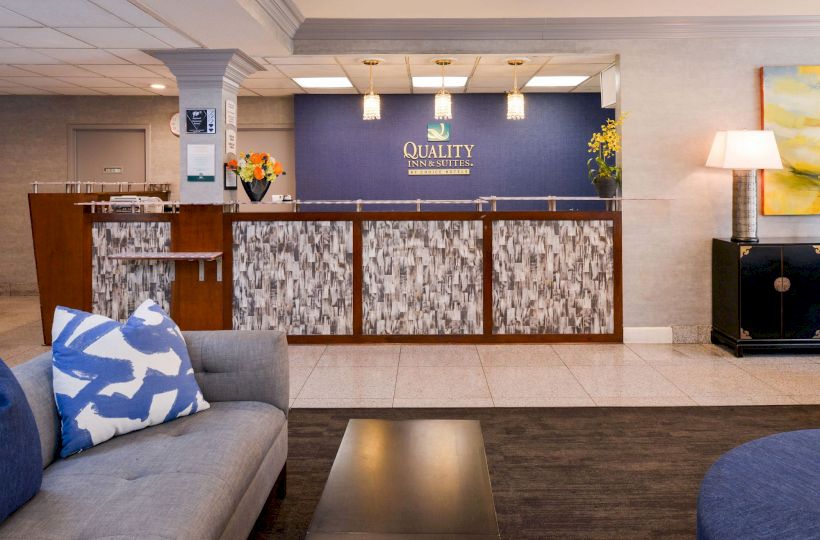 Image of a hotel lobby with a reception desk, blue and white decor, modern furniture, and warm lighting.