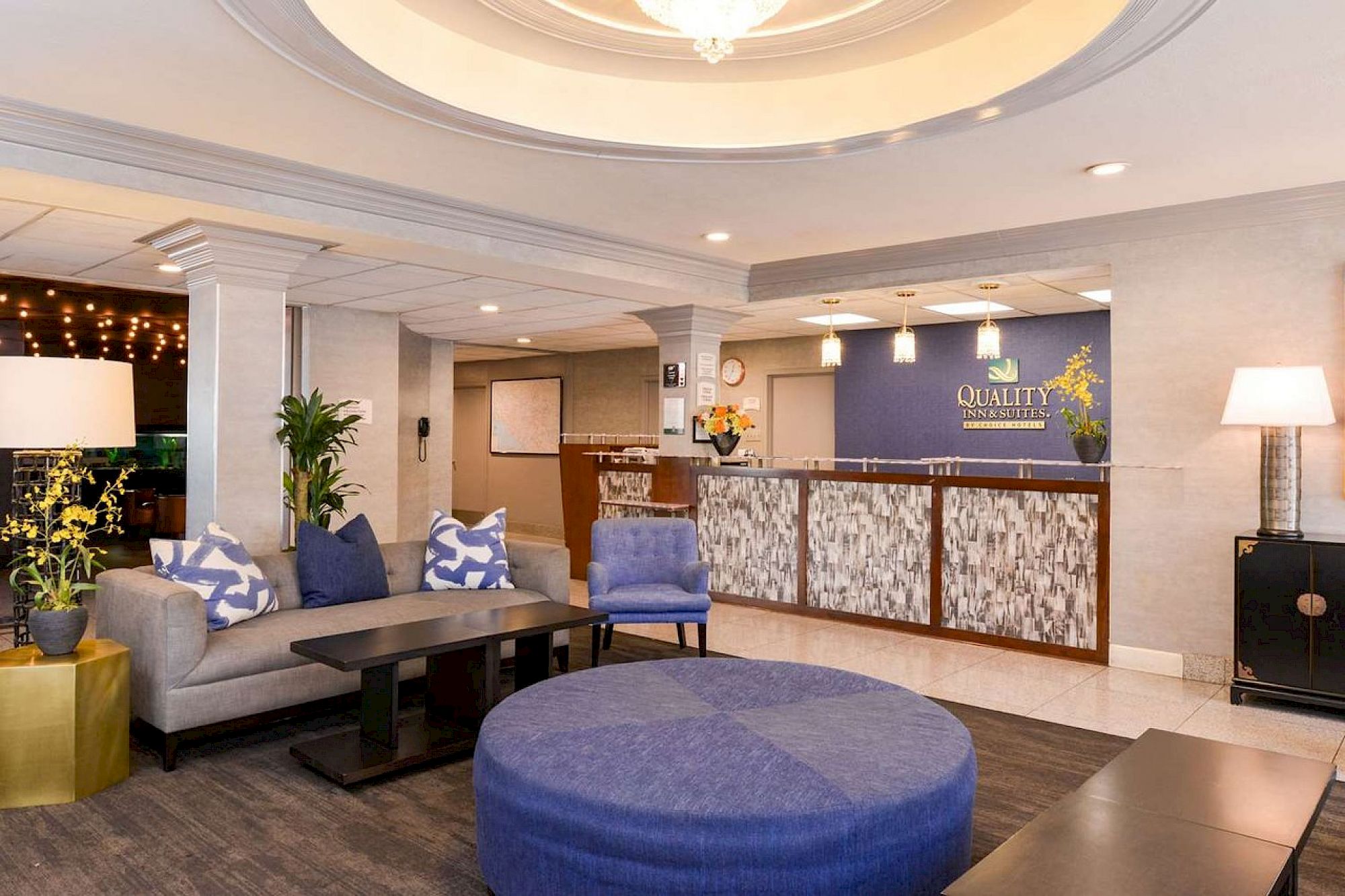 A hotel lobby with modern decor, featuring seating areas, a reception desk, and stylish lighting elements.